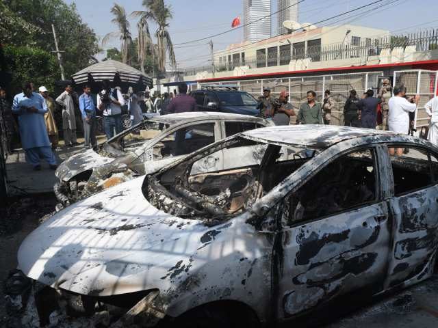 Pakistani security personnel stand next to burned out vehicles in front of the Chinese con