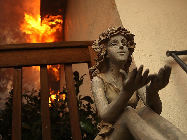 PARADISE, CA - NOVEMBER 08: A statue sits on the deck of a burning home as the Camp Fire m