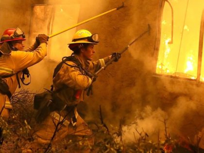 PARADISE, CA - NOVEMBER 09: Firefighters try to keep flames from burning home from spreadi