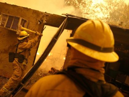 PARADISE, CA - NOVEMBER 09: Firefighters try to keep flames from burning home from spreading to a neighboring apartment complex as they battle the Camp Fire on November 9, 2018 in Paradise, California. Fueled by high winds and low humidity, the rapidly spreading Camp Fire ripped through the town of …