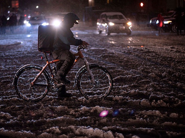 A man rides a bicycle through snow in New York on November 15, 2018 . - The National Weath