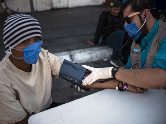 A health staffer checks the blood pressure of a Central American migrant, moving towards the United States in hopes of a better life, in the street in Mexicali, Baja California state, Mexico, on November 16, 2018. - The Central American migrant caravan faced a desperate situation Friday as its numbers …