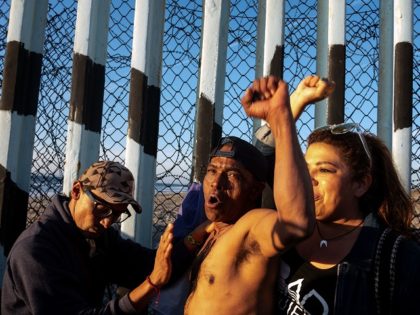 A Honduran migrant (C), cheers for Mexico as locals support him at the US-Mexico border wall in Playas de Tijuana, northwestern Mexico, November 18, 2018. - The Central American migrant caravan trekking toward the United States converged on the US-Mexican border Thursday after more than a month on the road, …