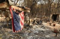 An American flag hangs at a burned out mobile home park in Paradise, California on November 18, 2018. - The family lost a home in the same spot to a fire 10 years prior. (Photo by Josh Edelson / AFP) (Photo credit should read JOSH EDELSON/AFP/Getty Images)