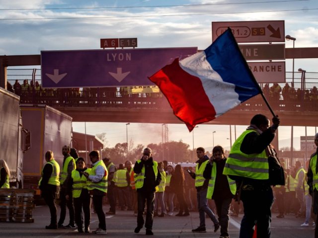 A "Yellow Vest" (Gilets Jaunes in French) protester waves a French flag on the A