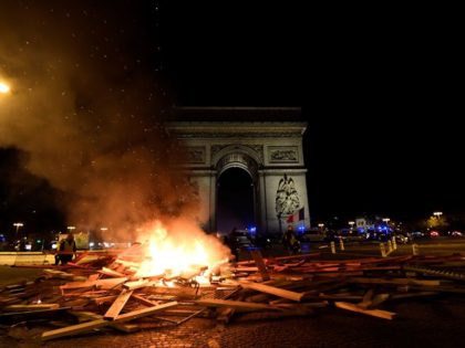 Material burns during a protest of the yellow vest (yellow vest) movement against rising oil prices and living costs as night falls, at The Arc de Triomphe on the Champs Elysees in Paris, on November 24, 2018. - Security forces in Paris fired tear gas and water cannon on November …