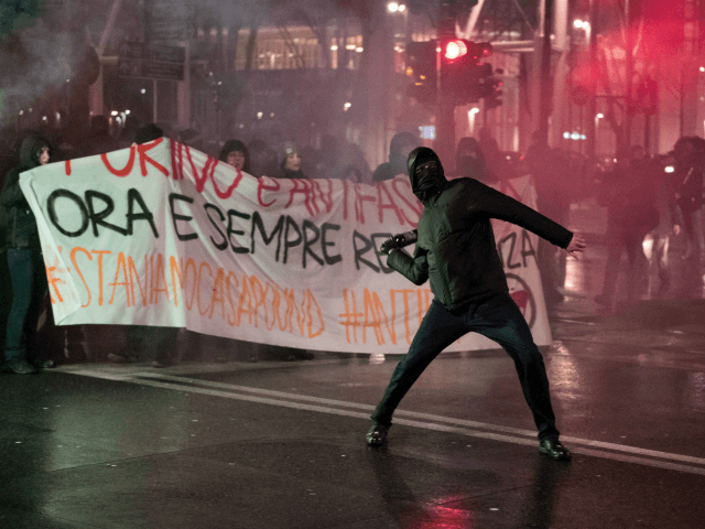 An Antifascist activist throws a bottle at police officers during a rally against an elect