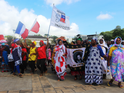 Protesters hold French and Mayotte flags as they gather on the Place de la Republique in M