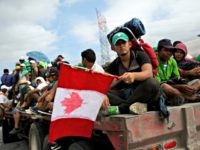 Honduran Migrant Honduran migrant Fernando Najar Guillen, 22, carries a handmade Canadian flag as he rides on the back of a flatbed truck with other Central Americans, outside Juchitan, Oaxaca state, Mexico, Thursday, Nov. 1, 2018. Najar said he plans to continue across the entire U.S. and seek work in Canada.