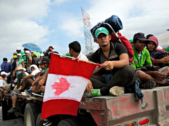 Honduran migrant Fernando Najar Guillen, 22, carries a handmade Canadian flag as he rides on the back of a flatbed truck with other Central Americans, outside Juchitan, Oaxaca state, Mexico, Thursday, Nov. 1, 2018. Najar said he plans to continue across the entire U.S. and seek work in Canada.