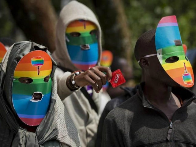FILE - In this Monday, Feb. 10, 2014 file photo, Kenyan gays and lesbians and others supporting their cause wear masks to preserve their anonymity and one holds out a wrapped condom, as they stage a rare protest, against Uganda's increasingly tough stance against homosexuality in solidarity with their counterparts …