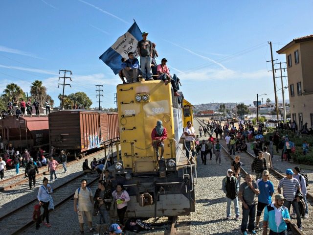A migrant waves an Honduran flag along the railroad tracks at the Mexico-U.S. border in Tijuana, Mexico, Sunday, Nov. 25, 2018, as a group of migrants tries to reach the U.S. The mayor of Tijuana has declared a humanitarian crisis in his border city and says that he has asked …