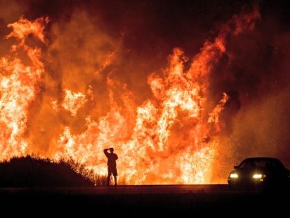 n this Dec. 6, 2017, file photo, a motorist on Highway 101 watches flames from the Thomas Fire, the largest wildfire on record in California, leap above the roadway north of Ventura, Calif. On Thursday, May 10, 2018, Gov. Jerry Brown signed an executive order that aims to reduce the …