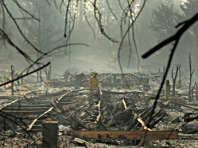 A firefighter searches for human remains in a trailer park destroyed in the Camp Fire, Friday, Nov. 16, 2018, in Paradise, Calif.
