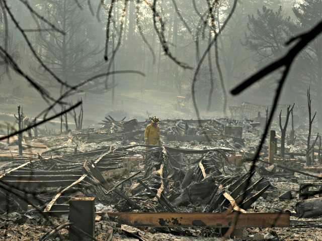 A firefighter searches for human remains in a trailer park destroyed in the Camp Fire, Fri