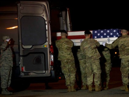 Members of the U.S. military carry a transfer case covered with an American flag during a