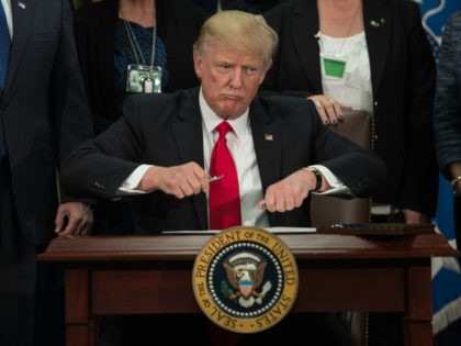 US President Donald Trump takes the cap off a pen to sign an executive order to start the Mexico border wall project at the Department of Homeland Security facility in Washington, DC, on January 25, 2017. / AFP PHOTO / NICHOLAS KAMM (Photo credit should read NICHOLAS KAMM/AFP/Getty Images)