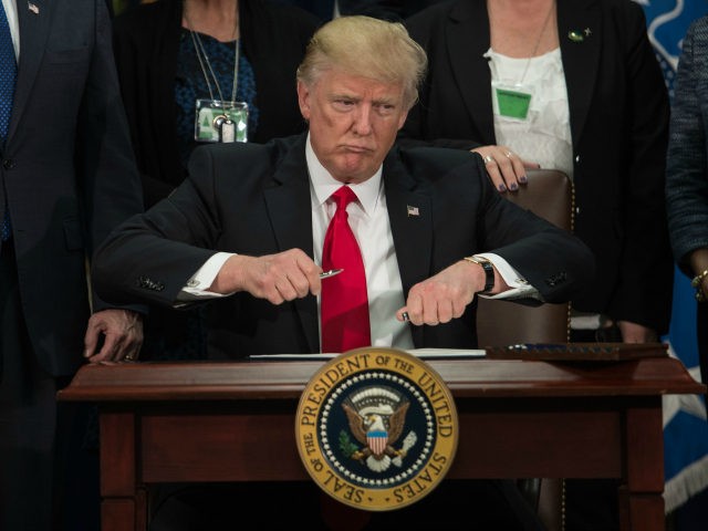 US President Donald Trump takes the cap off a pen to sign an executive order to start the Mexico border wall project at the Department of Homeland Security facility in Washington, DC, on January 25, 2017. / AFP PHOTO / NICHOLAS KAMM (Photo credit should read NICHOLAS KAMM/AFP/Getty Images)