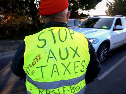 A man wears a Yellow Vest (Gilet jaune) reading 'stop taxes' during a demonstration of the movement against the rising of the fuel and oil prices on November 17, 2018 the entrance of Reims, northern France. - Thousands of drivers blocked roads across France in a 'yellow vest' movement against …