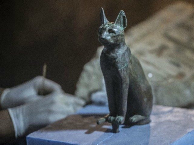 An Egyptian archaeologist cleans a bronze cat statue, discovered in Saqqara, south of the