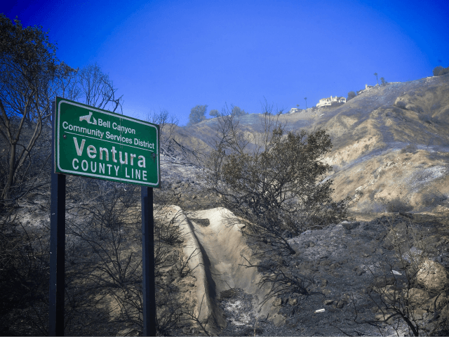 Homes remain intact overlooking fire-damaged hillsides near the border of Los Angeles and