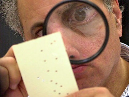 FILE - In this Nov. 24, 2000, file photo, Broward County, Fla. canvassing board member Judge Robert Rosenberg uses a magnifying glass to examine a disputed ballot at the Broward County Courthouse in Fort Lauderdale, Fla. The Founding Fathers set up the Electoral College to ensure a well-informed, geographically diverse …