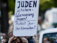 A participant shows a banner during a 'wear a kippah' gathering to protest against anti-Semitism in front of the Jewish Community House on April 25, 2018 in Berlin, Germany. The Jewish community made a public appeal for Jews and non-Jews to attend the event and wear a kippah as a …