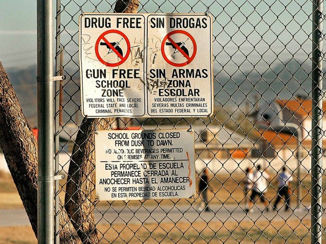 Drug and gun free school zone signs are shown as students play basketball at an elementary