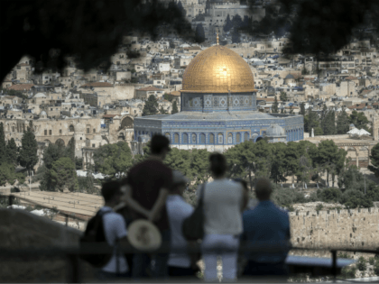Tourists listen to a guide during a visit at Mount of Olives in east Jerusalem overlooking