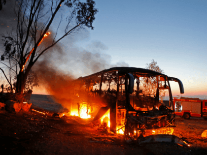 A picture taken on November 12, 2018 shows a bus set ablaze after it was hit by a rocket f