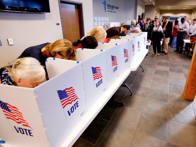 A growing line of voters, right, wait as others fill out their paper ballots in privacy vo