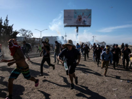 Central American migrants run along the Tijuana River near a border crossing after Border Patrol agents used tear gas on November 25, 2018. Guillermo Arias/AFP/Getty Images