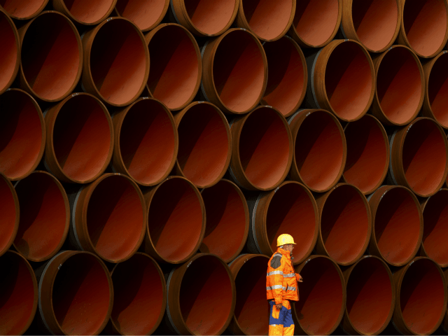 A worker walks in front of pipes which lie stacked at the Nord Stream 2 facility at Mukran on Ruegen Islandon October 19, 2017 in Sassnitz, Germany. Nord Stream is laying a second pair of offshore pipelines in the Baltic Sea between Vyborg in Russia and Greifswald in Germany for …