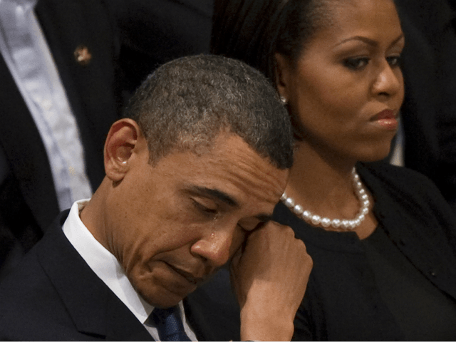 US President Barack Obama wipes away a tear as he sits next to First Lady Michelle Obama a