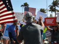 WEST PALM BEACH, FL - MARCH 24: A President Donald Trump supporter wearing an NRA hat (who didn't want to give his name) speaks with people gathered as close as they can, to where President Donald Trump is residing at his Mar-a-Lago club, for a March For Our Lives event …