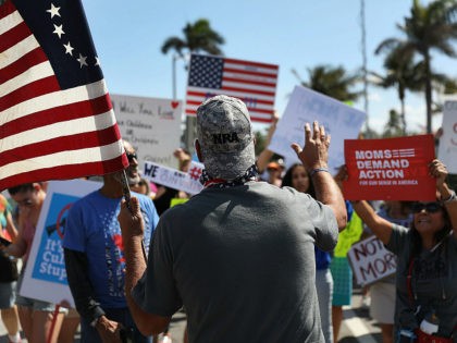 WEST PALM BEACH, FL - MARCH 24: A President Donald Trump supporter wearing an NRA hat (who didn't want to give his name) speaks with people gathered as close as they can, to where President Donald Trump is residing at his Mar-a-Lago club, for a March For Our Lives event …