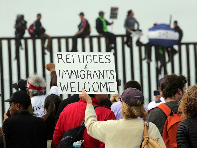 SAN DIEGO, CA - APRIL 29: Pro-migrant caravan demonstrators rally at the west end of the U.S.-Mexico border as pro-migrant demonstrators climb the border wall from the Mexican side on April 29, 2018 in San Diego, California. More than 300 immigrants, the remnants of a caravan of Central Americans that …