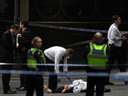 A police officer (C) inspects a body at the crime scene following a stabbing incident in Melbourne on November 9, 2018. - A knife-wielding attacker killed one person and injured two others in a rush hour stabbing rampage in downtown Melbourne on November 9, before being shot and captured by …