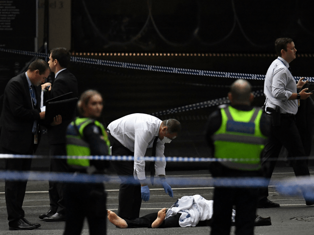 A police officer (C) inspects a body at the crime scene following a stabbing incident in Melbourne on November 9, 2018. - A knife-wielding attacker killed one person and injured two others in a rush hour stabbing rampage in downtown Melbourne on November 9, before being shot and captured by …