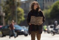 A homeless person begs on a center divider in San Francisco, California