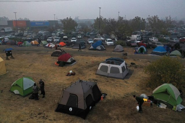 Volunteers set up camp for California wildfire evacuees outside a supermarket in Chico, near the devastated community of Paradise Trump to visit as more than 1,000 missing in California fire
