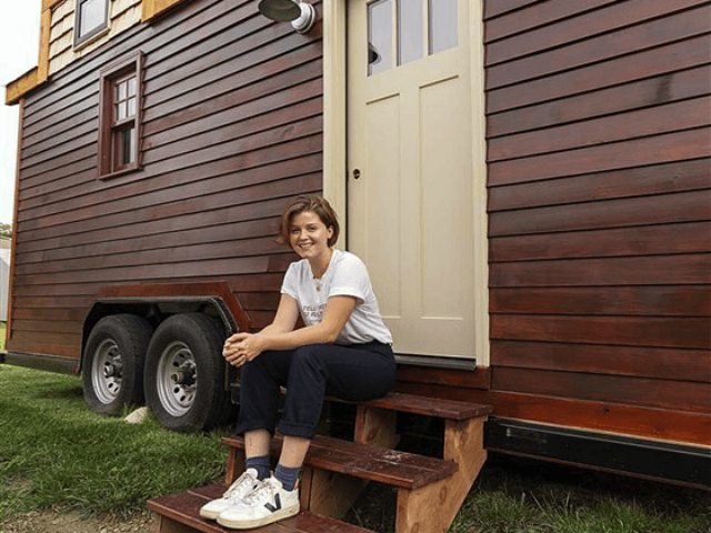 Meghan Panu sits on the front steps of her house in St. Louis. The 12-foot-tall house was