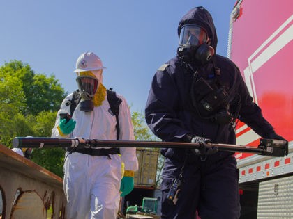 Service members from the 24th Civil Support Team and the U.S. Coast Guard Atlantic Strike Team conducts a 360-degree perimeter patrol to check the radiation levels of a simulated collapsed building at the Urban Search and Rescue Yard in Baltimore, during Vigilant Guard 18 on May 9, 2018. The team, …