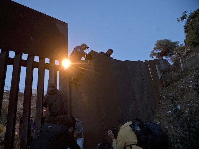 A Honduran migrant helps other immigrants cross to the U.S. side of the border wall, in Tijuana, Mexico, Sunday, Dec. 2, 2018. Thousands of migrants who traveled via caravan are seeking asylum in the U.S., but face a decision between waiting months or crossing illegally, because the U.S. government only …