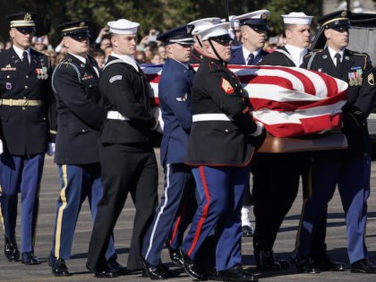 The flag-draped casket of former President George H.W. Bush is carried by a joint services