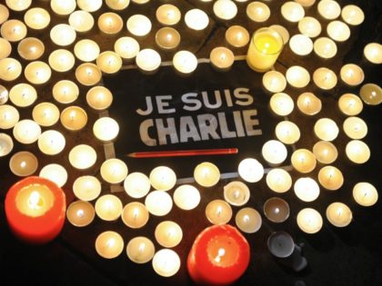 Candles are placed next to a sign reading 'Je suis Charlie' (I am Charlie) and a