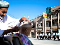 A police patrol passes a barber near the Id Kah Mosque in the old town of Kashgar, in China's Xinjiang Uighur Autonomous Region, after the morning prayer on Eid Al Fitr on June 26, 2017.