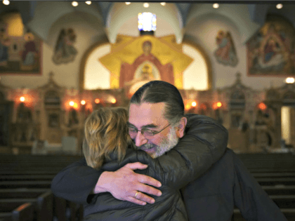 Rev. Nicholas Jonas hugs a longtime parishioner of Holy Trinity Greek Orthodox Church, whi