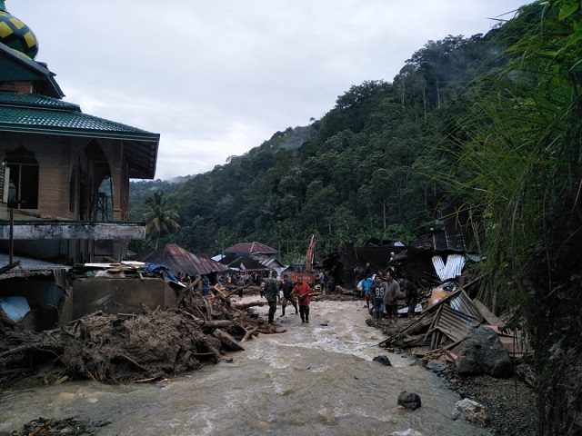 Villagers wade through flood water at the Saladi village in Mandailing Natal, North Sumatra on October 13, 2018. - At least 10 people are dead when heavy rain led to flash floods and landslide in Indonesia, an official said on October 13. (Photo by AGUS SALIM / AFP) (Photo credit …