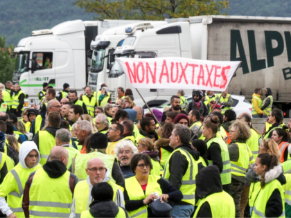 Demonstrators wearing Yellow Vests (Gilets jaunes) hold banner as they block the traffic d